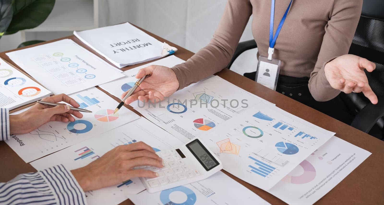 Businessman meeting marketing plan, using calculator to calculate numbers on stock market graph paper for analysis. Meeting to discuss company ideas by wichayada