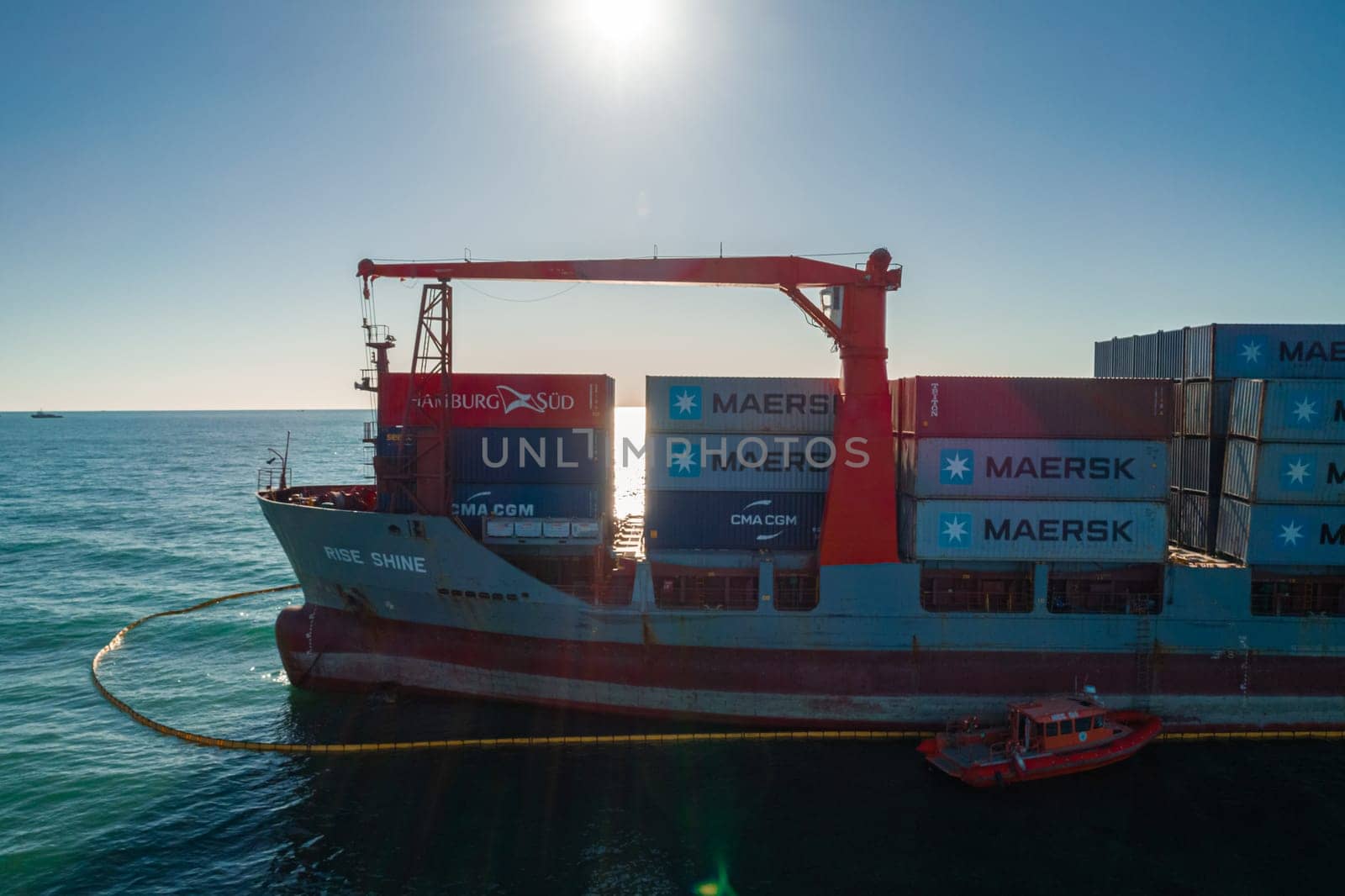 Aerial view of a RISE SHINE container cargo ship stands aground after a storm with floating boom around the ship to prevent the spread of petroleum. Container ship ran aground during the storm.