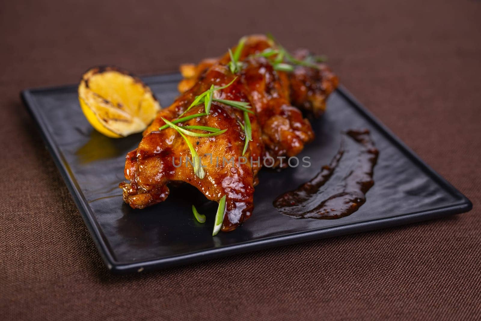 Grilled chicken wings in sweet tangy sauce with lemon slices. Perfect appetizer for a party or gathering. Delicious and flavorful dish.