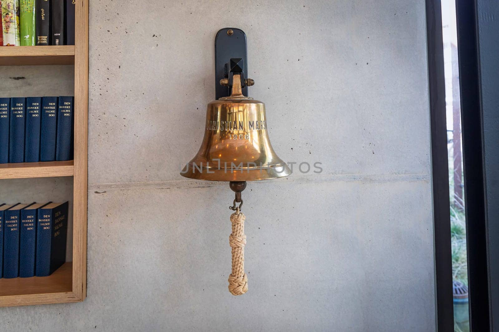 Brass bell on a gray wall indoors. Herlev, Denmark - April 4, 2024.