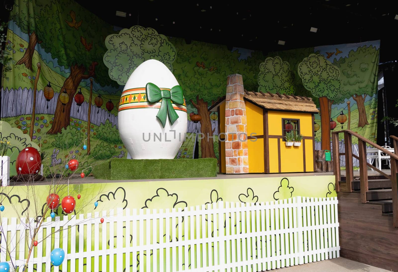 Easter decoration for children on stage with a yellow house and a large easter egg. Children's theater.
