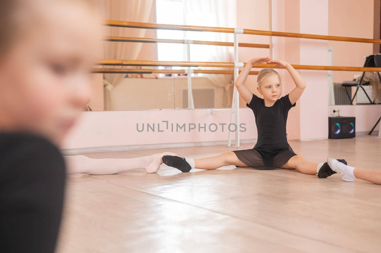 Little girls sit in a circle and do stretching at a ballet school. by mrwed54