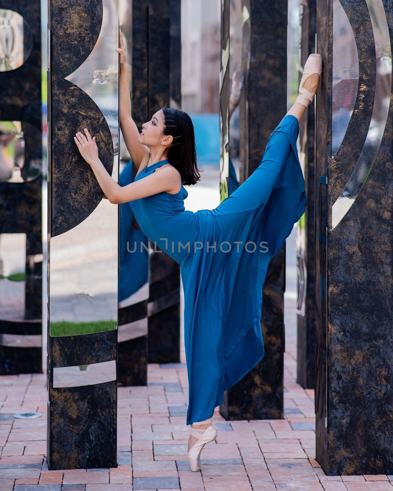 Beautiful asian ballerina in blue dress and pointe shoes posing outdoors