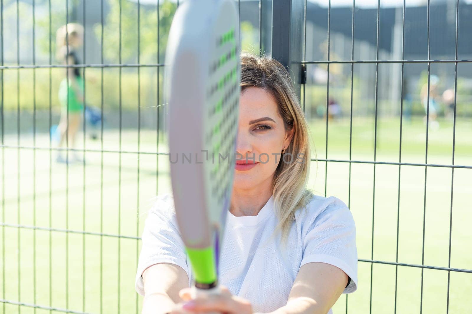 Happy female paddle tennis player during practice on outdoor court looking at camera. Copy space. High quality photo