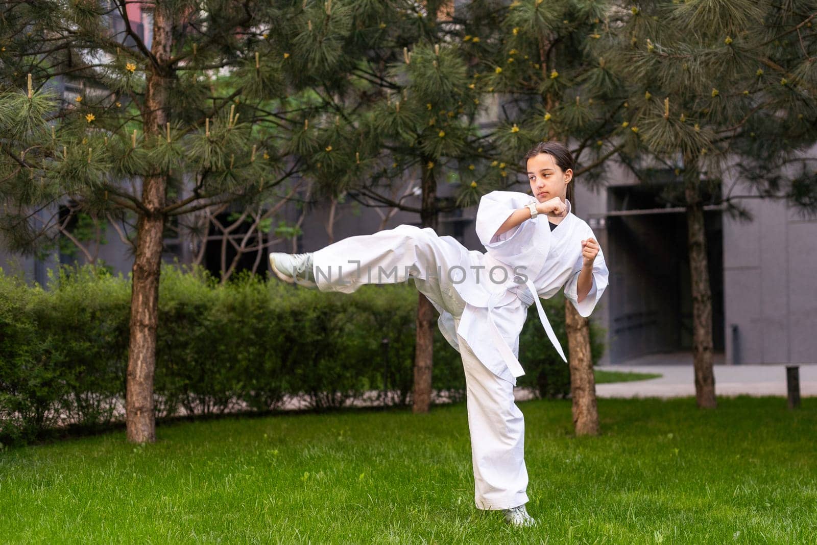 Young active girl wearing in white kimono with white belt performing martial arts kick skills. sporty karate woman improving fight technique on Chinese bridge. concept of sport. High quality photo