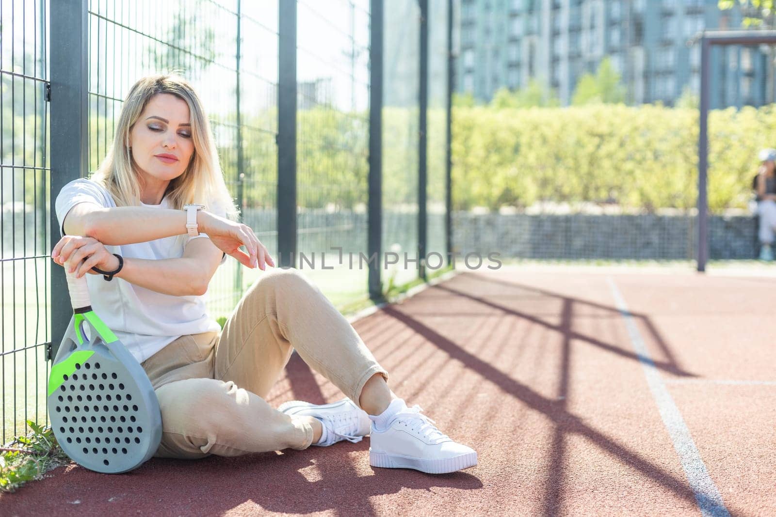 Happy female paddle tennis player during practice on outdoor court looking at camera. Copy space. High quality photo