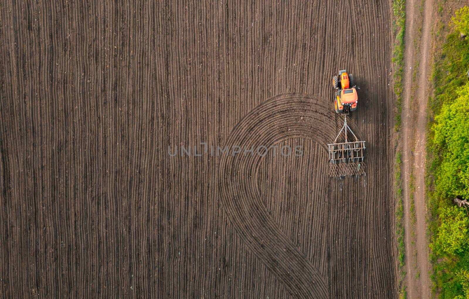 Tractor plows field in the spring. Aerial top view, Wheat seed planting company
