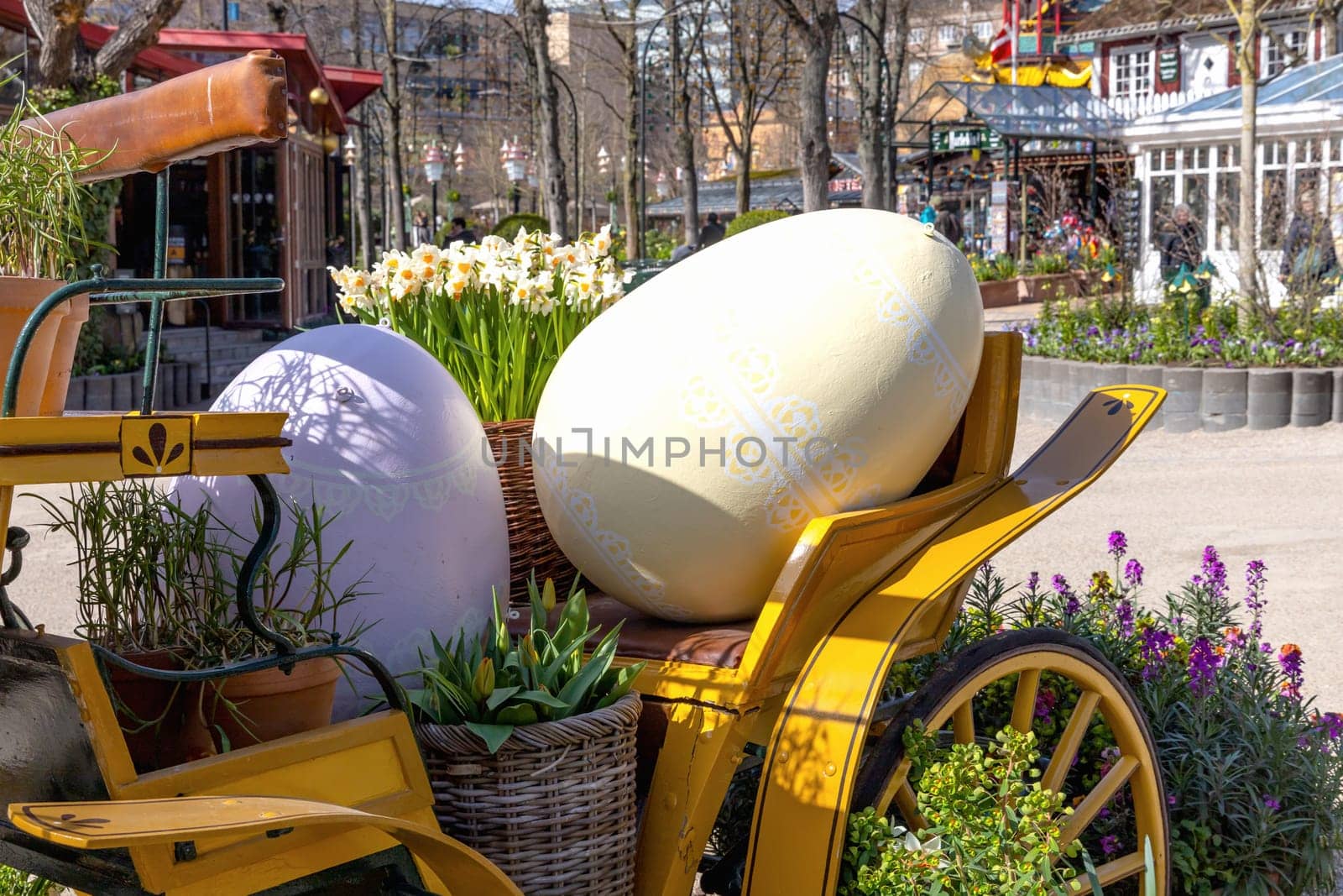 Easter decoration of a carriage with large decorative Easter eggs in a city park.