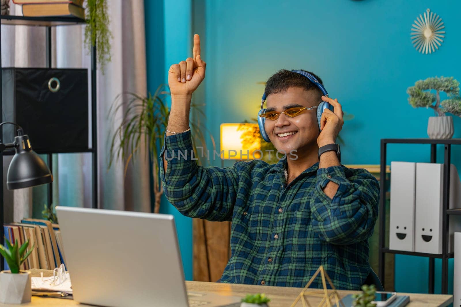 Indian man with laptop scream in delight triumph winner gesture celebrate success win money in lottery online casino game good news. Excited Hispanic guy sitting at home office workplace. Lifestyle