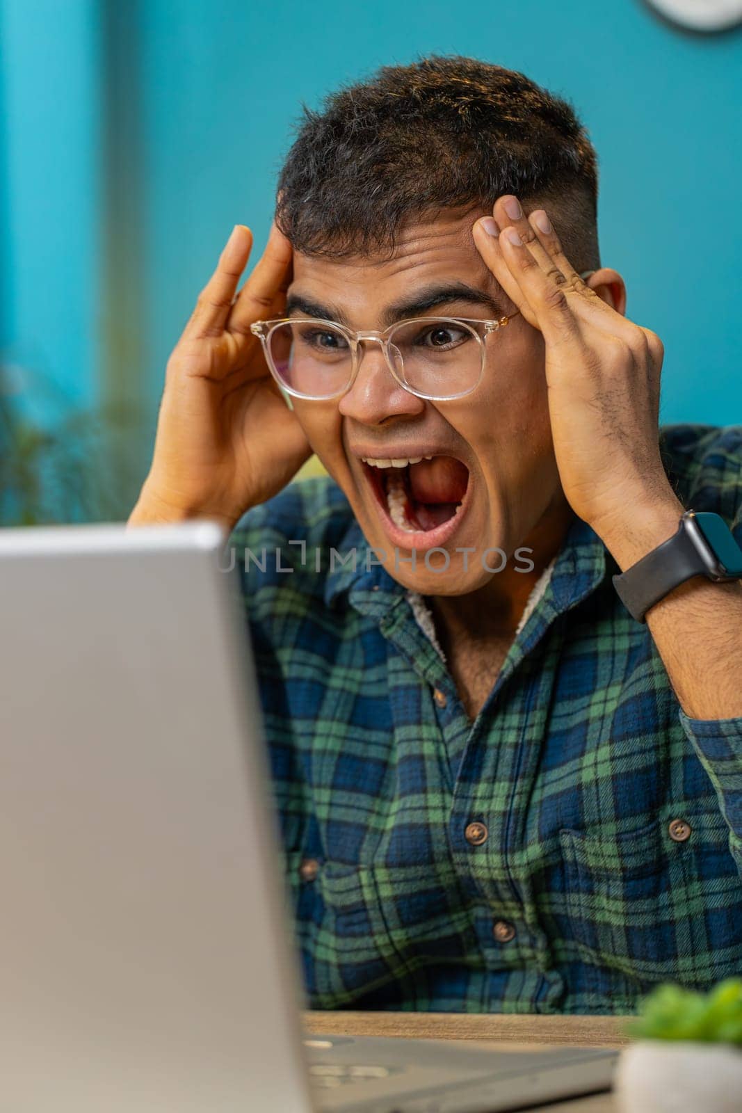 Angry Indian man having software problems with laptop angry guy nervous seeing error or mistake notification at computer screen mad employee experience virus attack or app malfunction. Vertical