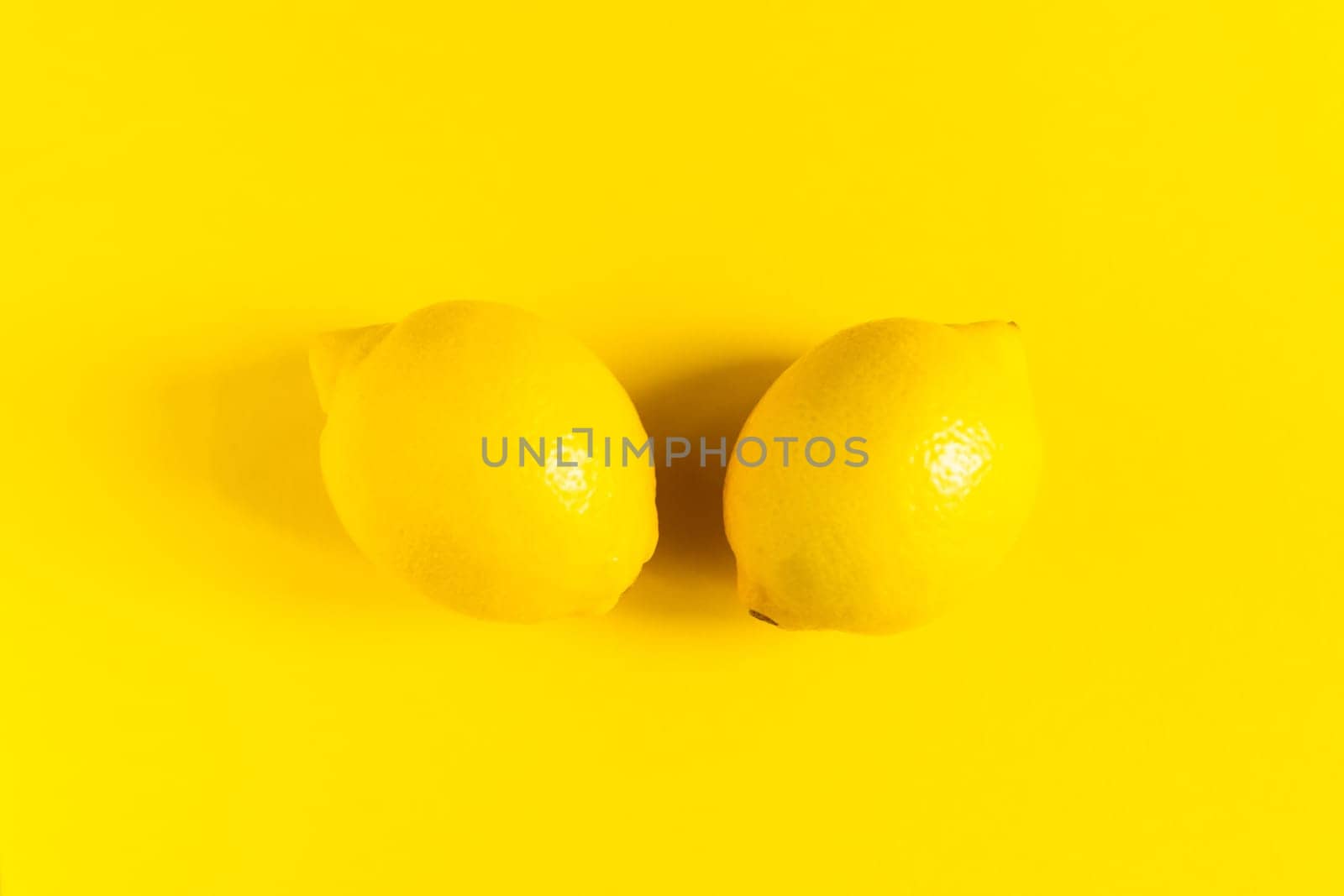 Juicy lemons on a bright yellow background, citrus minimal concept. Flat lay, top view, copy space.