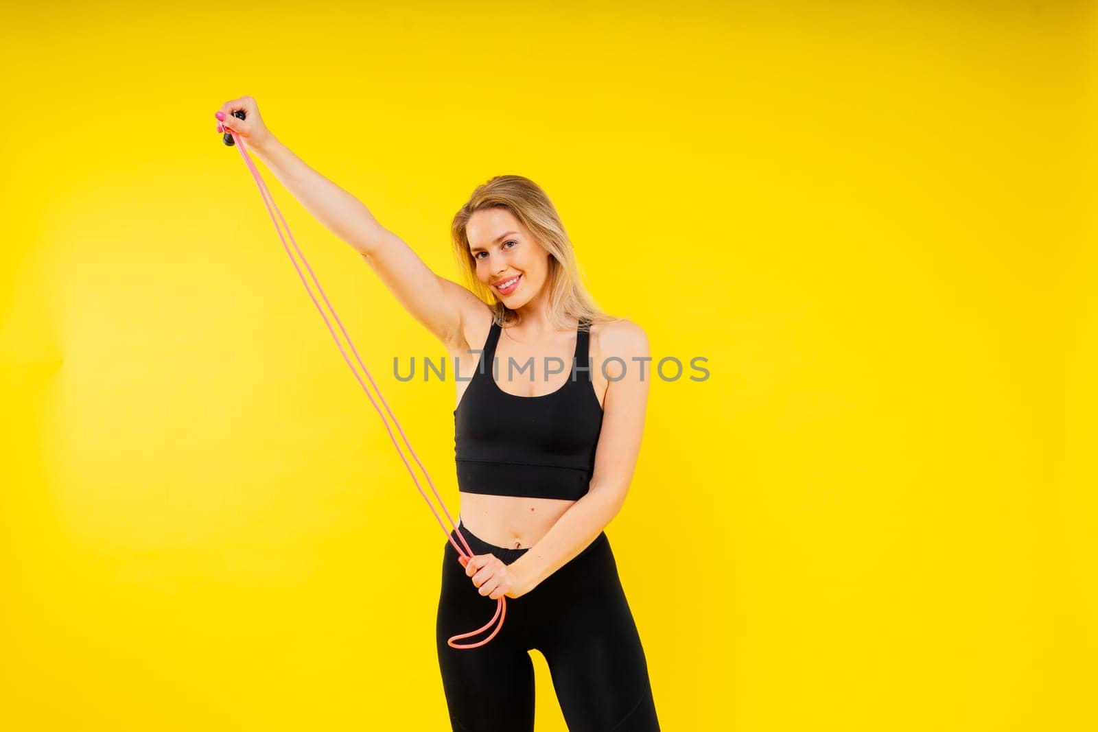 Blond woman with jump rope in studio, yellow red and dark background by Zelenin