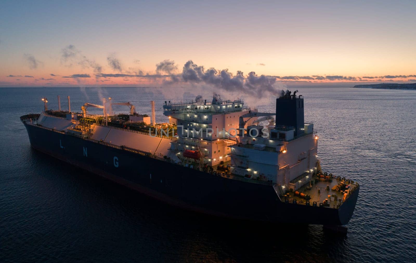 A large LNG tanker docks at an industrial port terminal for cargo operations at dusk by Busker