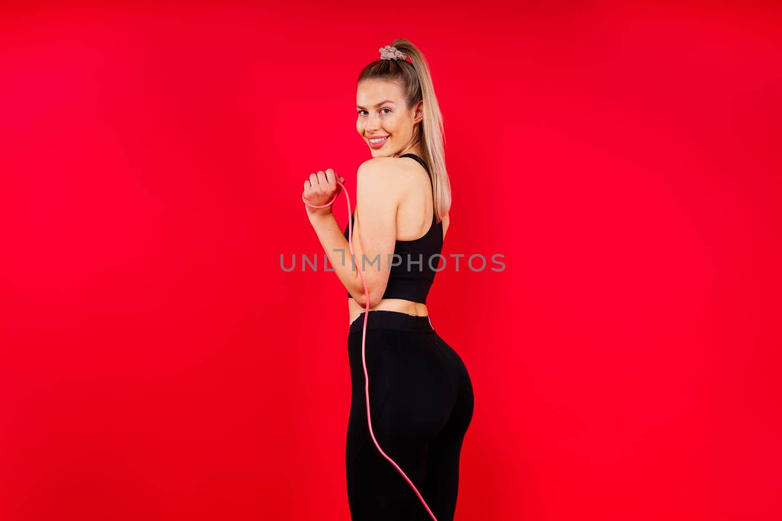 Blond woman with jump rope in a studio, yellow red and dark background