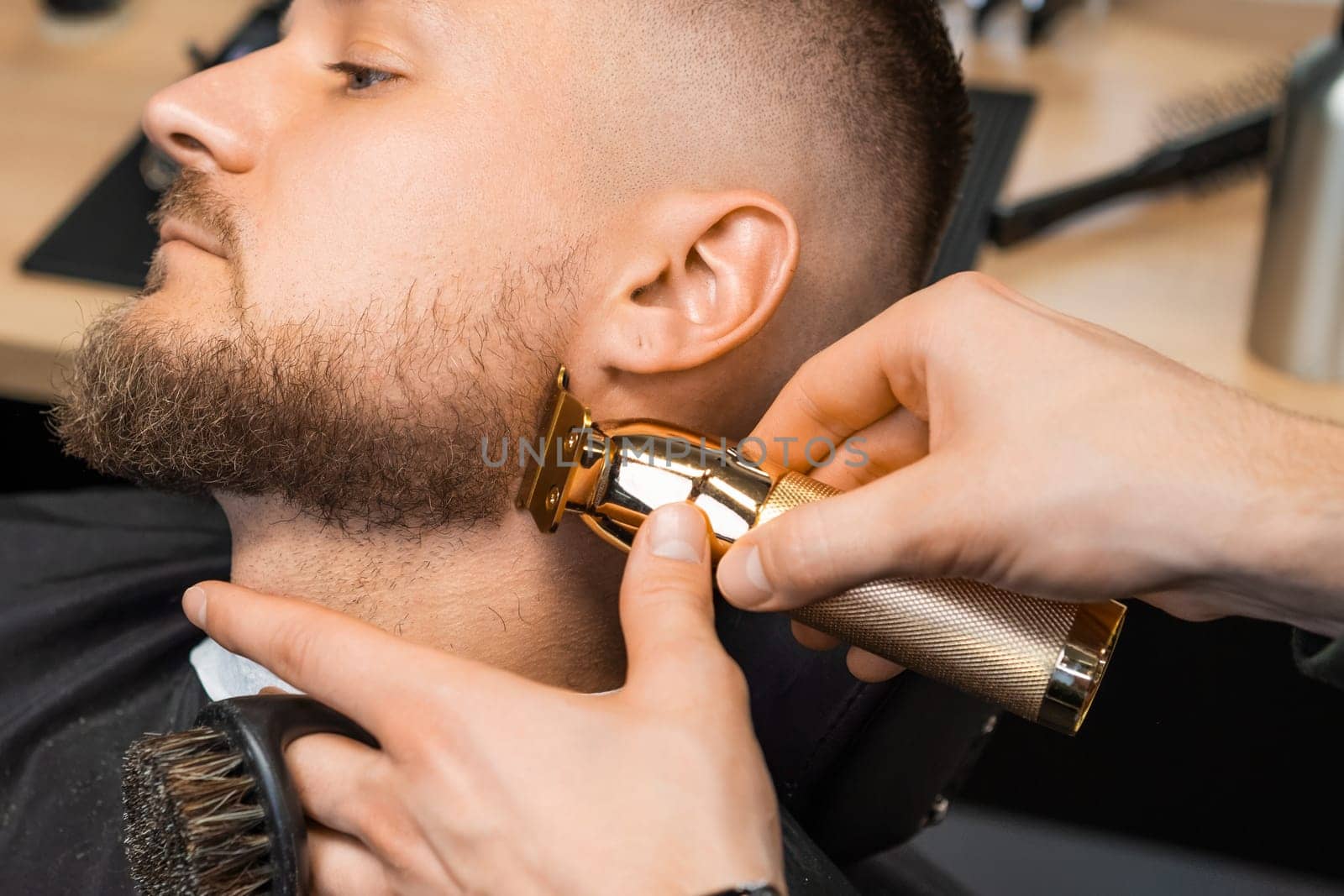 The hairstylist trims the brunette clients hair at the barbershop