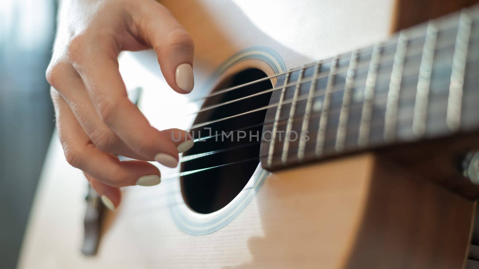 Close-up of female hands on an acoustic guitar. The girl learns to play the guitar.