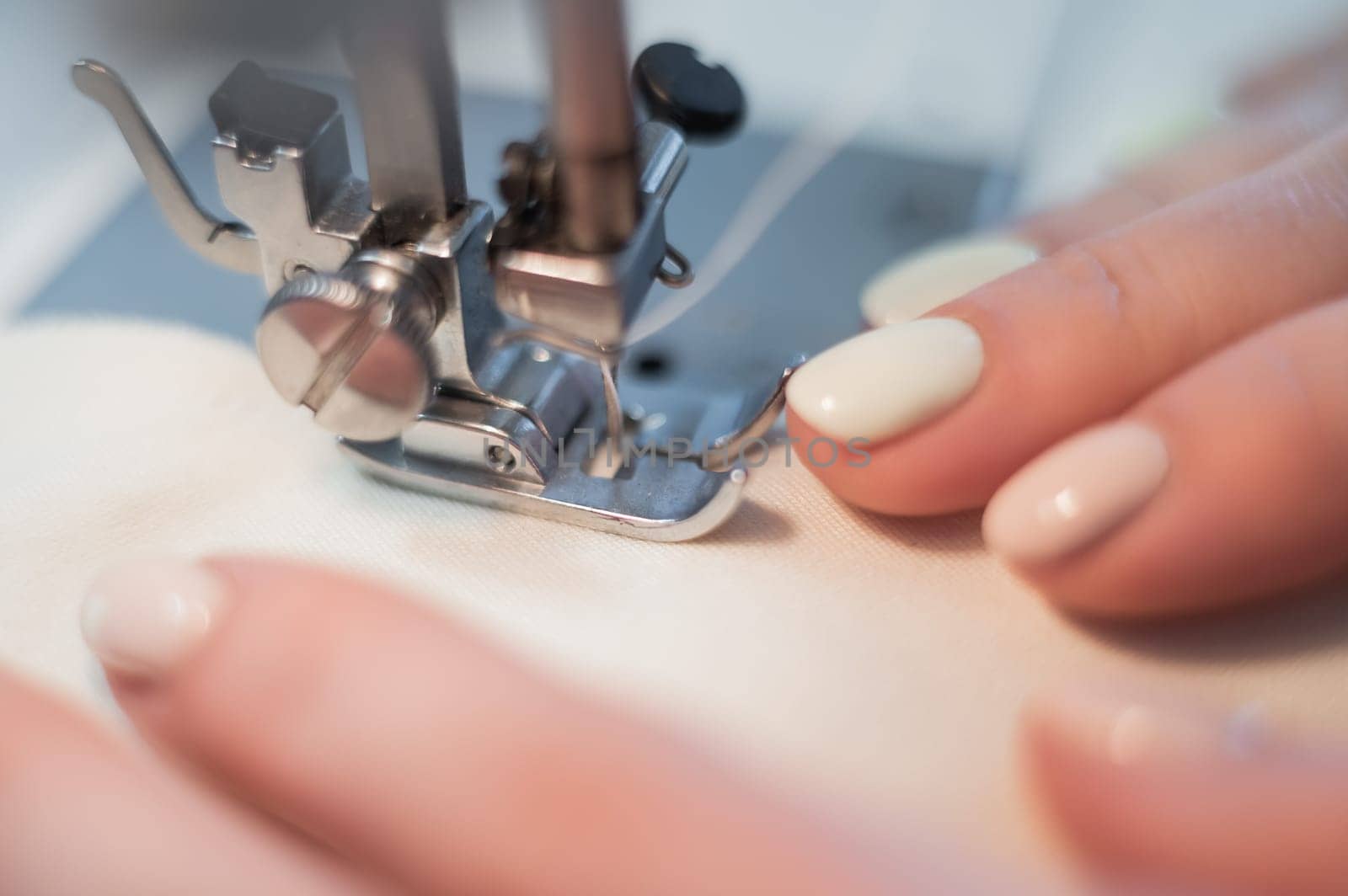 Close-up. A woman works on an electric sewing machine at home.