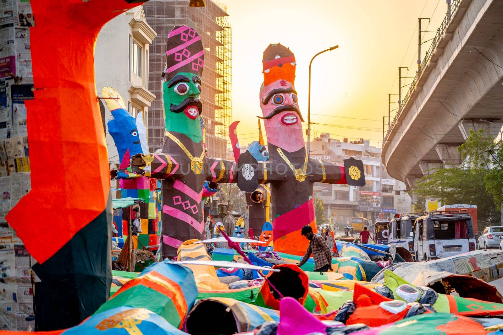 poor indian laborer standing in front of huge colorful paper effigies of Ravan made on the hindu festival of Dussehra by Shalinimathur
