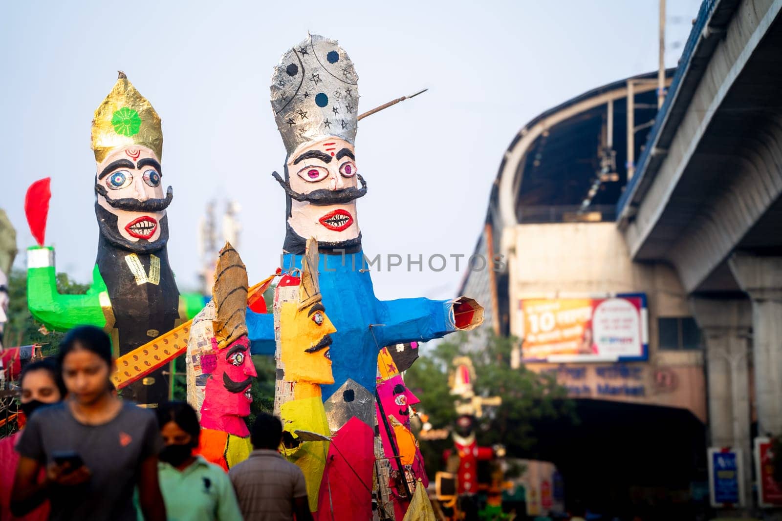 People walking in front of huge colorful effigies of Ravana made of paper on the hindu festival of Dussehra Vijayadashami by Shalinimathur