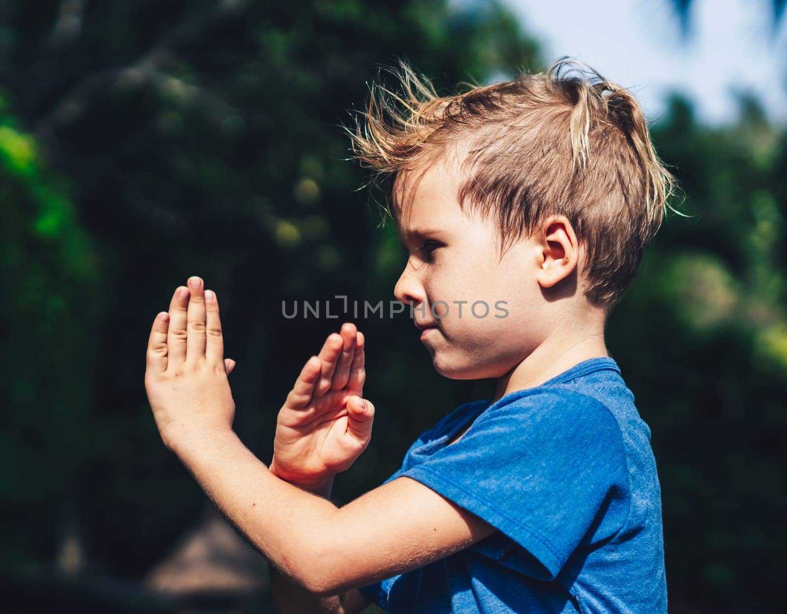 Child boy blue t-shirt karate pose, playing outside summer day. Happy childhood, family education.