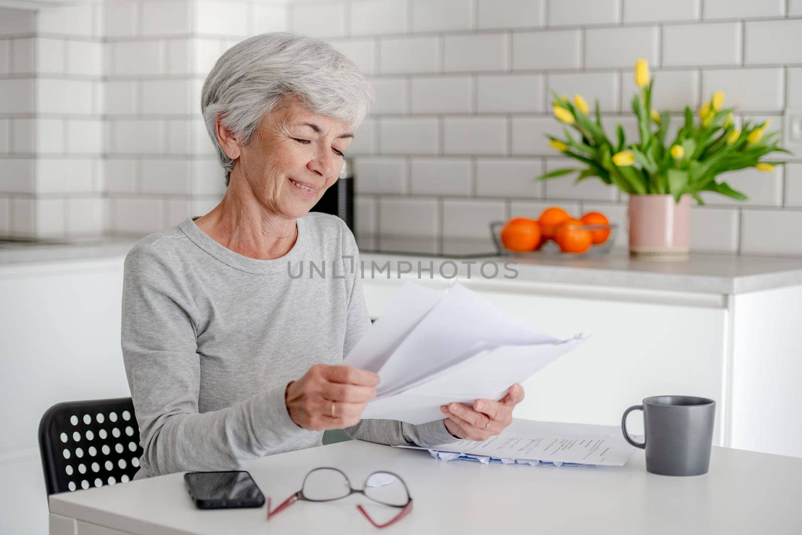 Woman With Grey Hair Examines Documents At Home