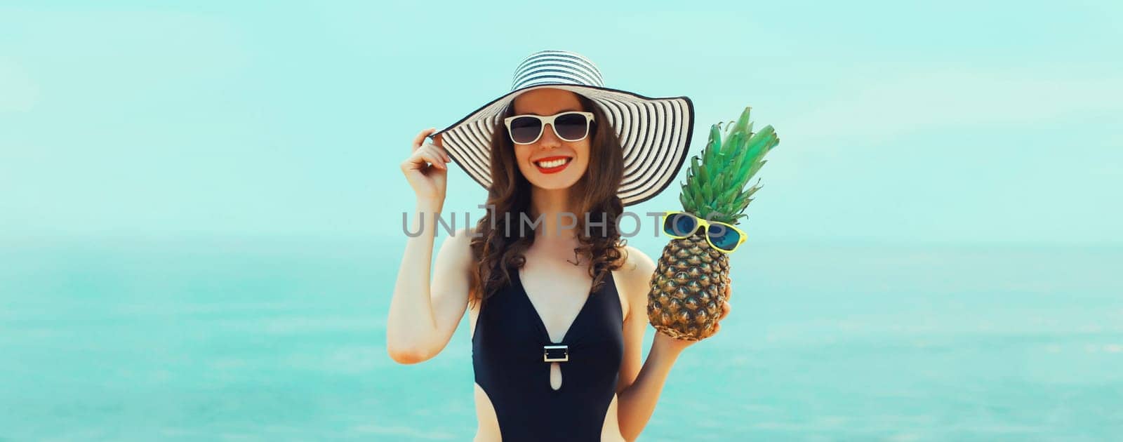 Summer vacation, beautiful happy woman in bikini swimsuit, hat, pineapple fruits on the beach at sea by Rohappy