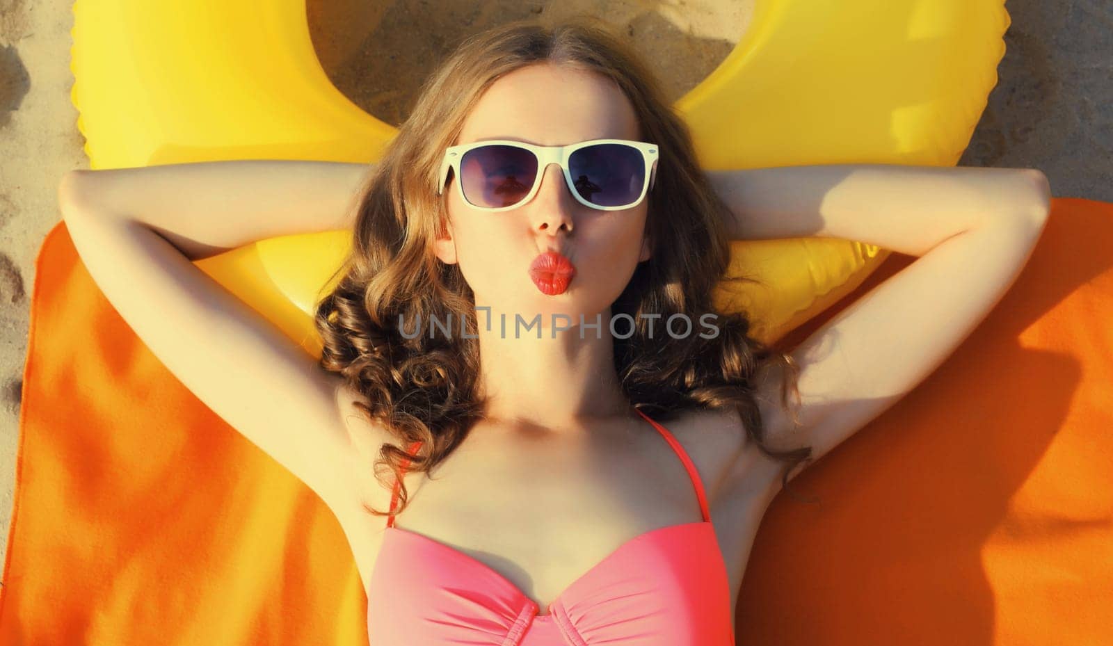 Summer vacation, happy relaxing young woman lying on sand on the beach with swimming inflatable ring