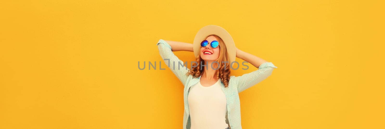 Happy caucasian relaxed young woman enjoying sunny warm day wearing summer straw hat, sunglasses posing on bright yellow background, copy space