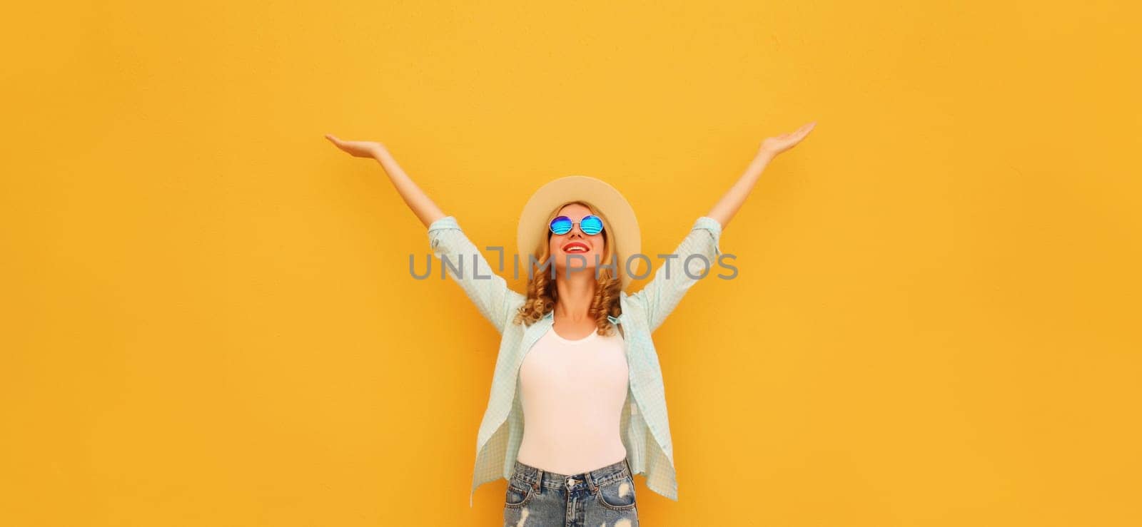 Summer holidays, inspired happy cheerful smiling young woman raising her hands up wearing denim clothing, straw hat on colorful yellow background