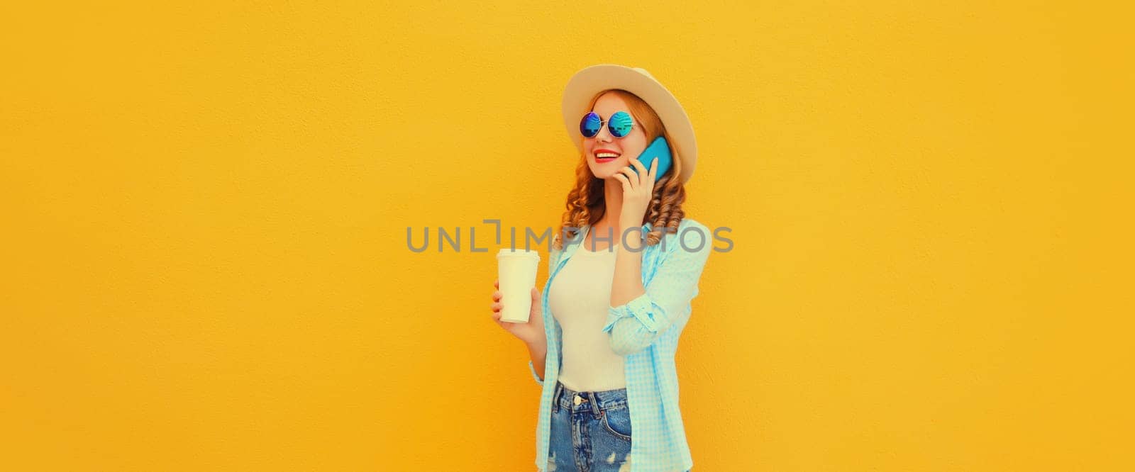Happy cheerful smiling young woman calling on mobile phone wearing summer hat on yellow background by Rohappy