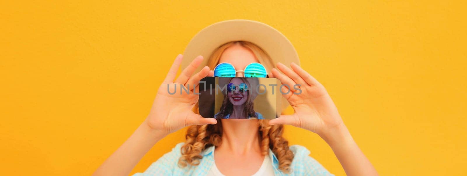 Summer moment, close up of modern happy young woman taking selfie with smartphone stretching her hands on yellow background