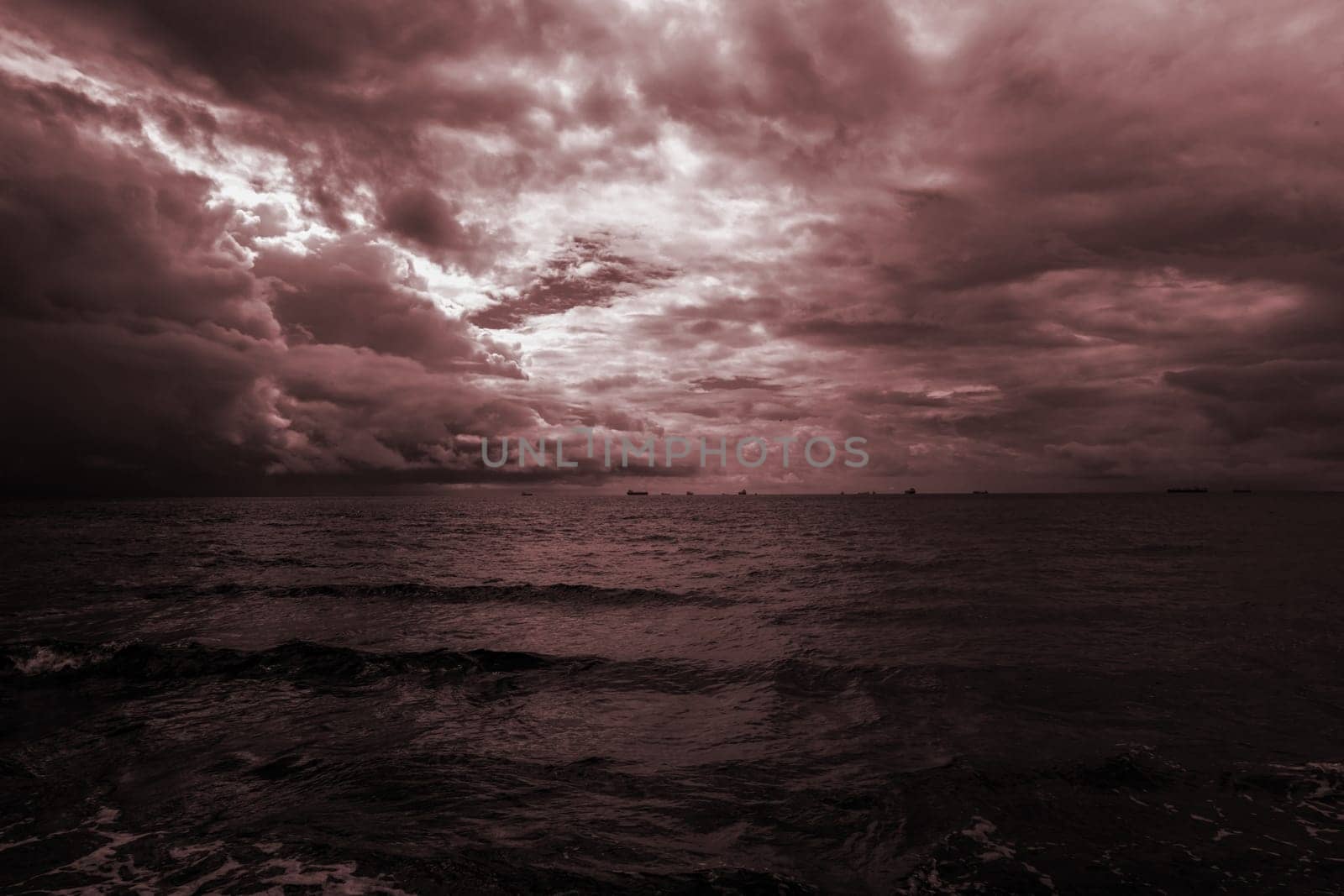 Dramatic evening seascape in dark burgundy colors. Purple sky with clouds over the sea. High quality photo