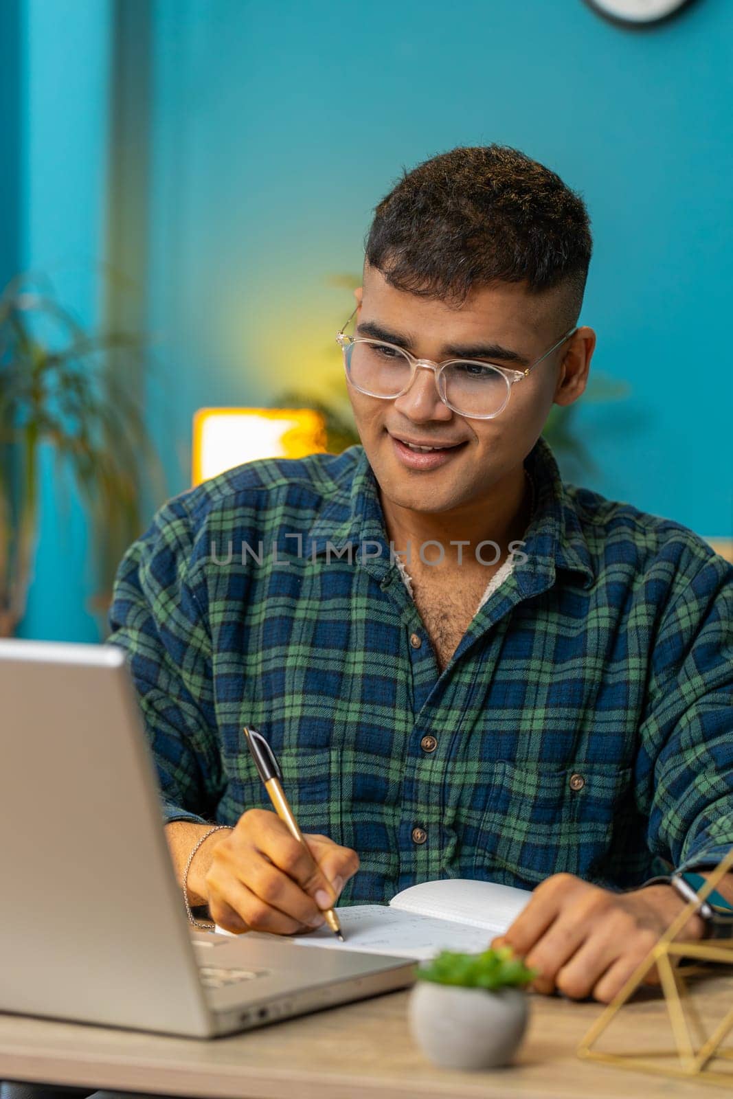 Hindu man student freelancer study with notebook write notes making conference video call talking to webcam on laptop computer. Online teacher e-learning in remote chat. Distance education online