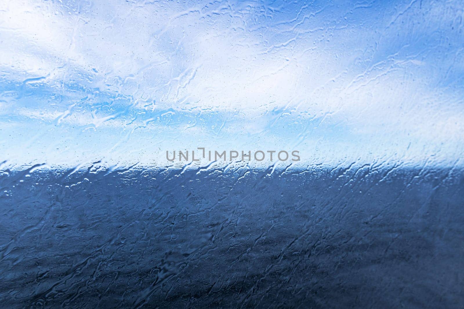 Raindrops on the window overlooking the sea. Background with sea and sky on a rainy day. High quality photo