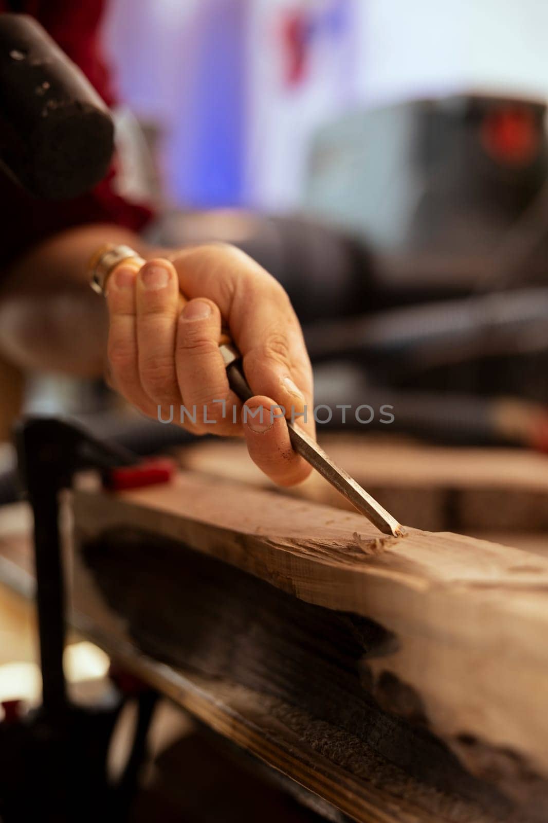 Manufacturer meticulously carving intricate designs into wood using chisel and hammer in carpentry shop. Carpenter in woodworking workshop shaping wooden pieces with tools, close up shot
