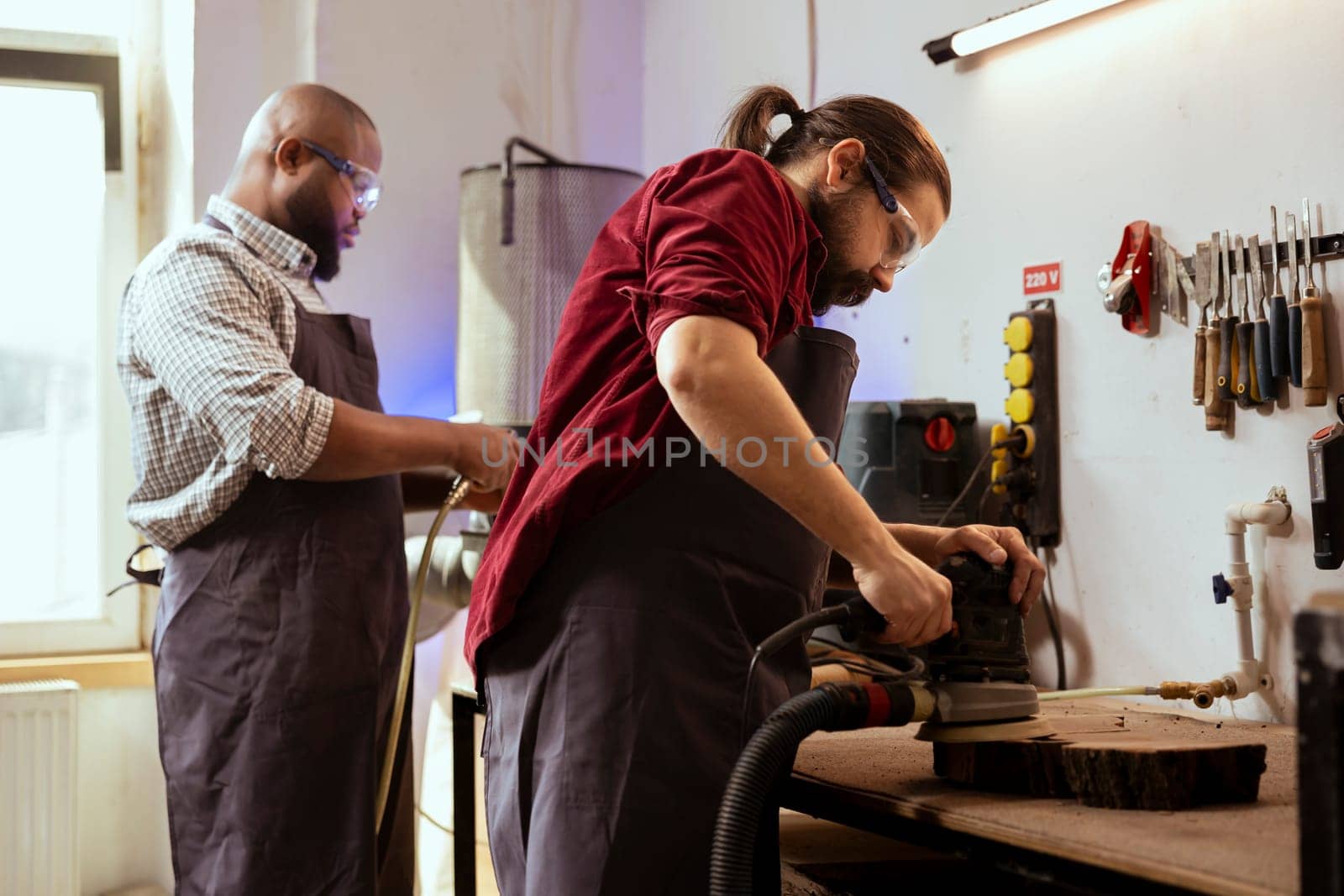 Man and coworker using angle grinder on wood block for professional results by DCStudio