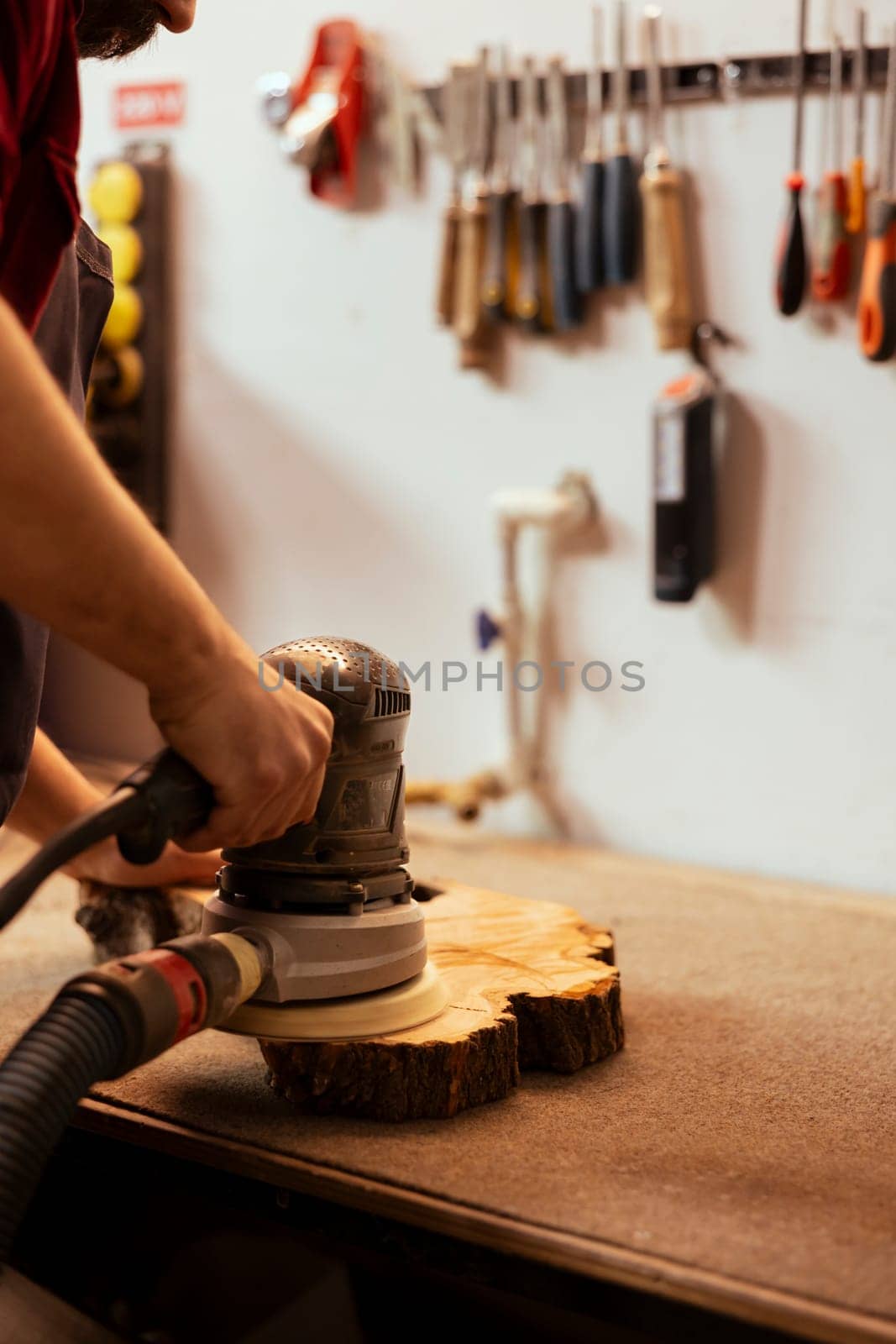 Woodworking specialist in assembly shop uses angle grinder on wood by DCStudio
