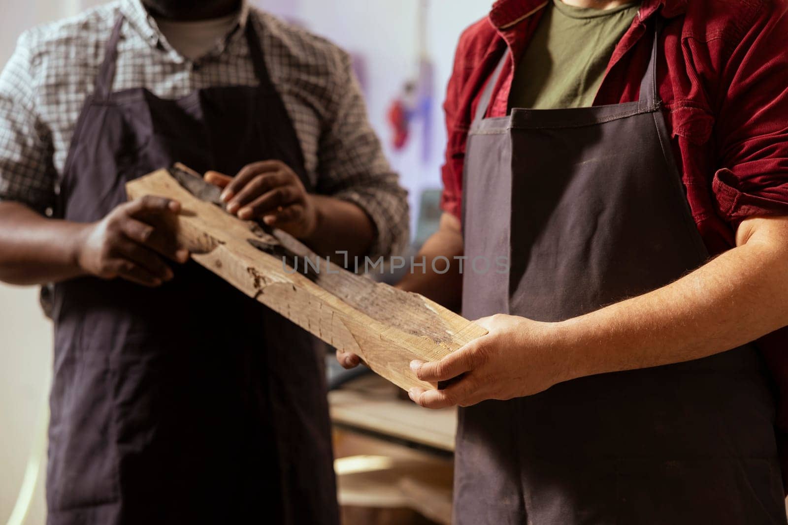 Manufacturer and apprentice selecting high quality wood materials, ensuring they align with project requirements. Cabinetmaker and colleague doing quality assurance on lumber piece, close up shot