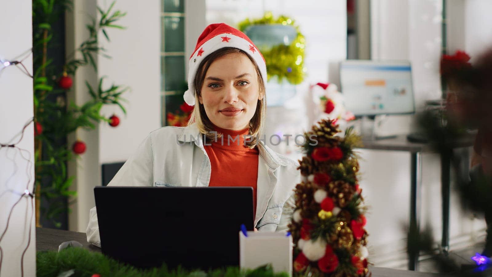 Close up portrait of bookkeeper in Christmas decorated office checking documents for accuracy. Employee solving tasks at computer desk in xmas ornate workspace during winter holiday season
