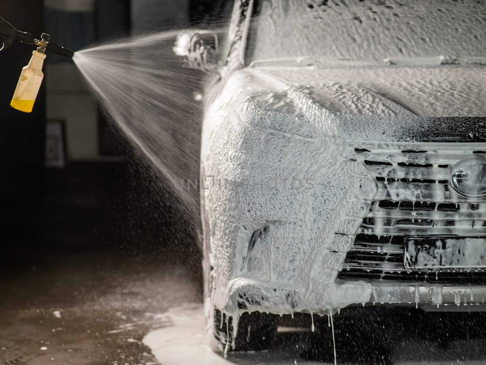 Man applying foam to black car in car wash