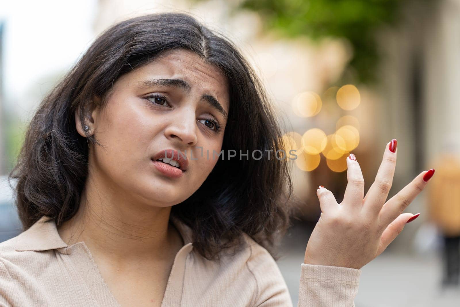 Sad unhappy Indian young woman thinks over life concerns suffers from unfair situation outdoors. Problem feeling bad annoyed burnout grief. Hispanic girl alone on urban city street. Town lifestyles