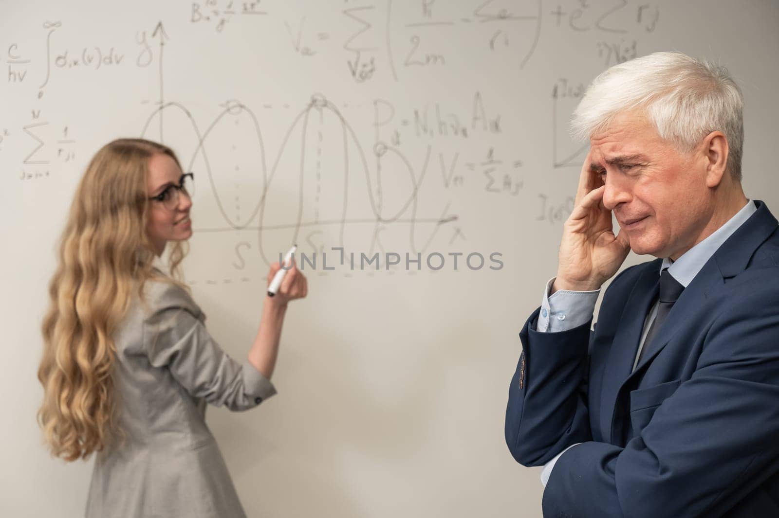 Female student answers a question from an elderly professor at a white board. by mrwed54