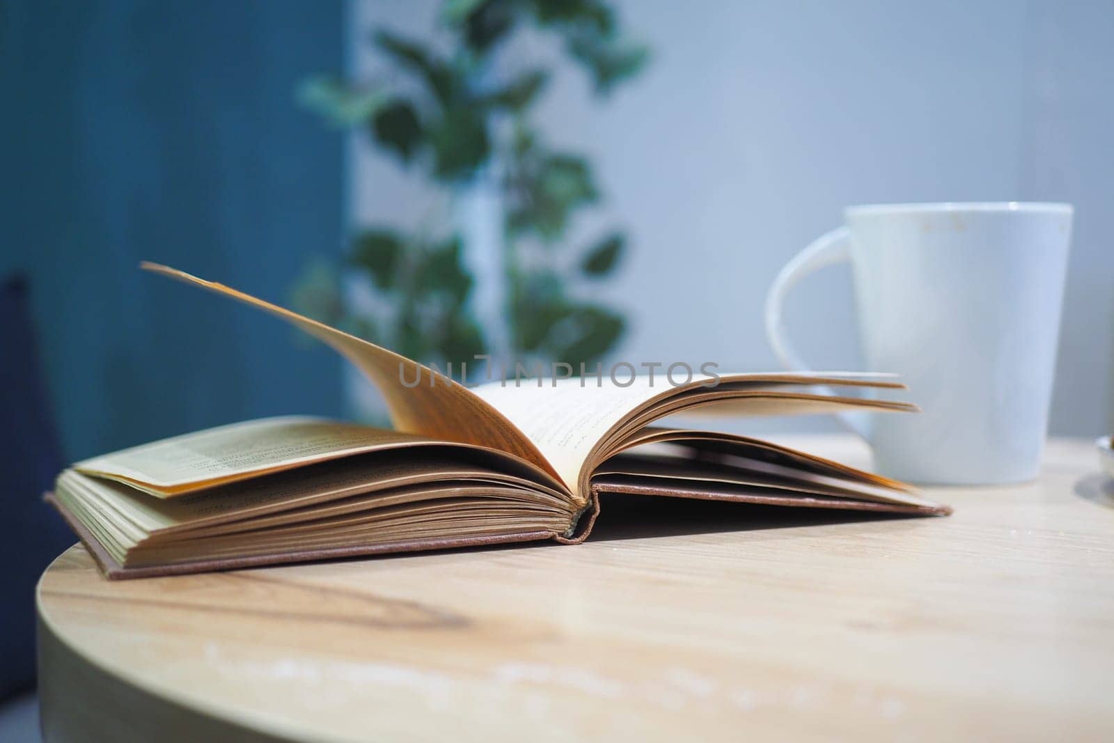 a open book and a coffee cup on a cafe table .