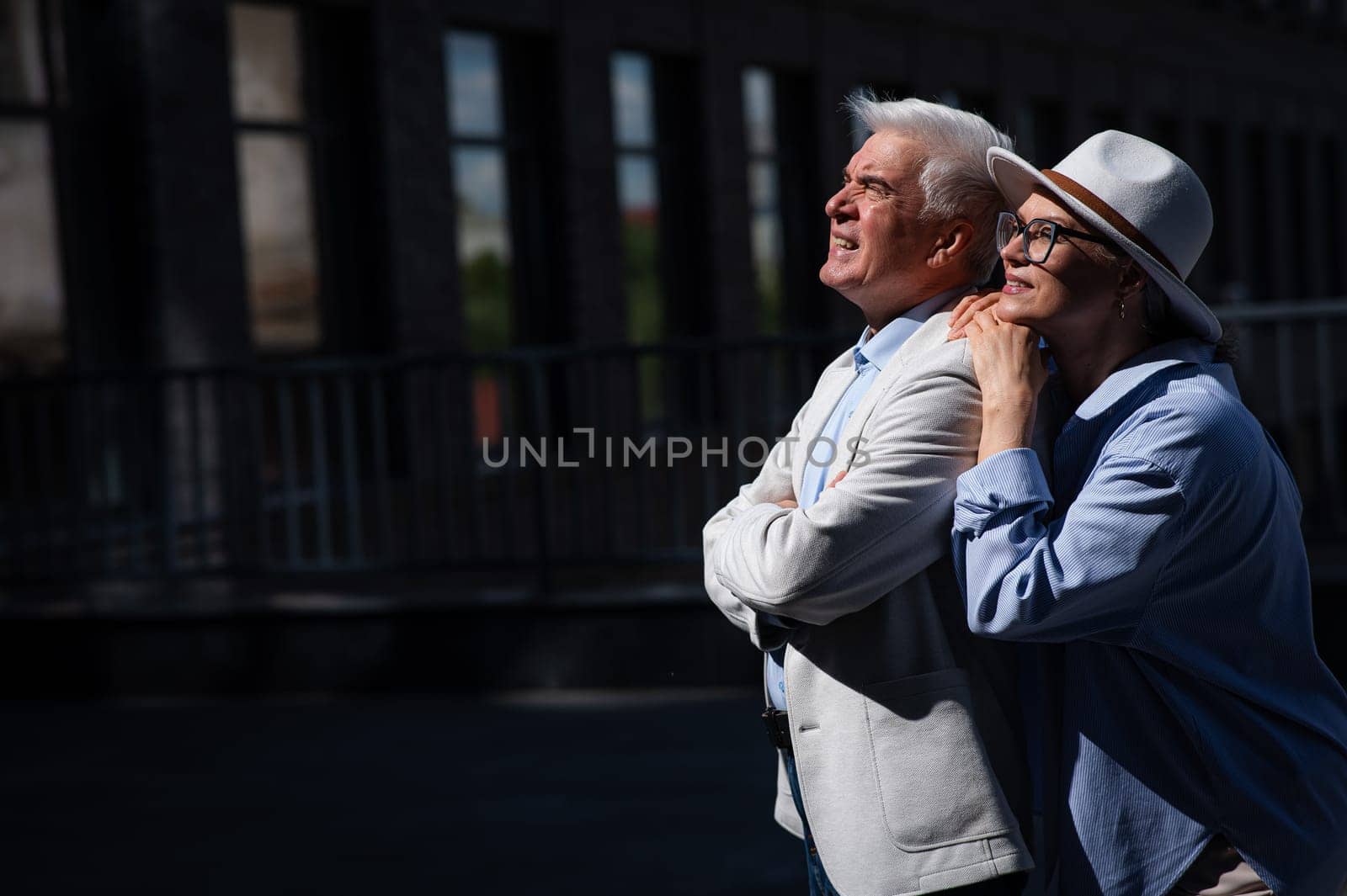 Stylish mature couple on a walk. Portrait of gray-haired man and woman hugging outdoors