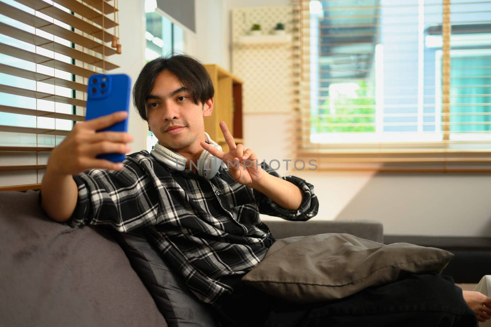 Young Asian man taking a selfie or talking on a video call on smartphone by prathanchorruangsak