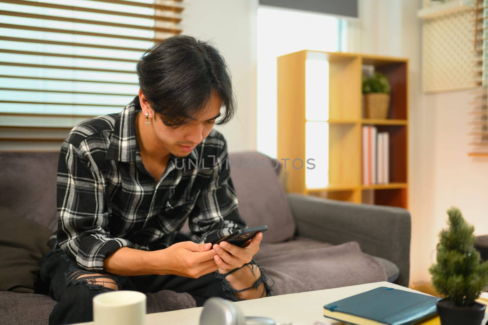Young man browsing internet and texting online on mobile phone.