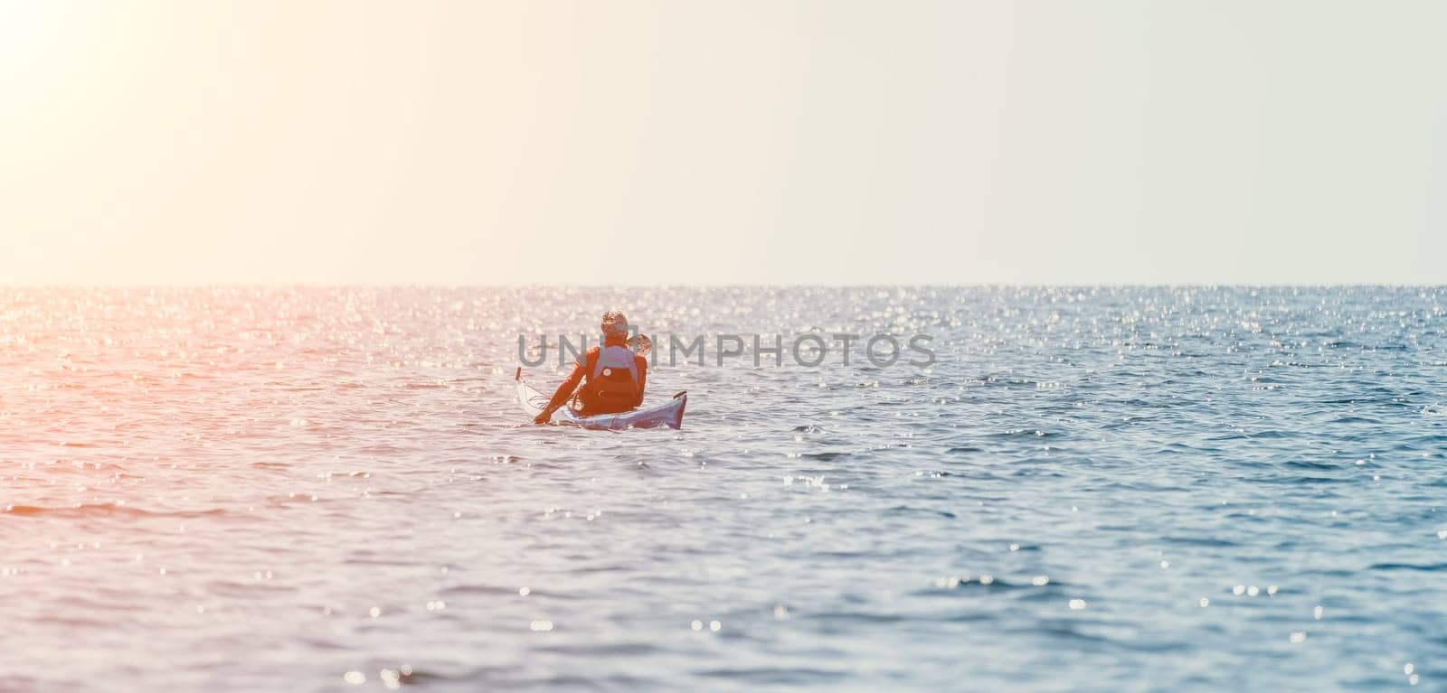 Man sea kayak. Happy free man in kayak on ocean, paddling with wooden oar. Calm sea water and horizon in background. Active lifestyle at sea. Summer vacation. by panophotograph