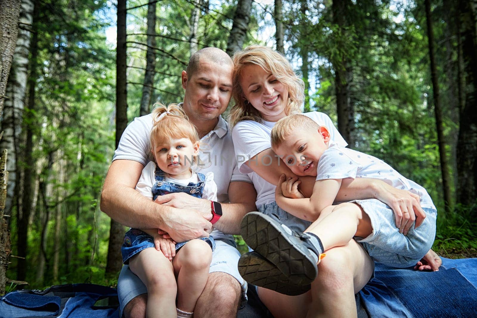 A man, woman, and child having fun and playing in the forest or park in summer or spring sunny day by keleny