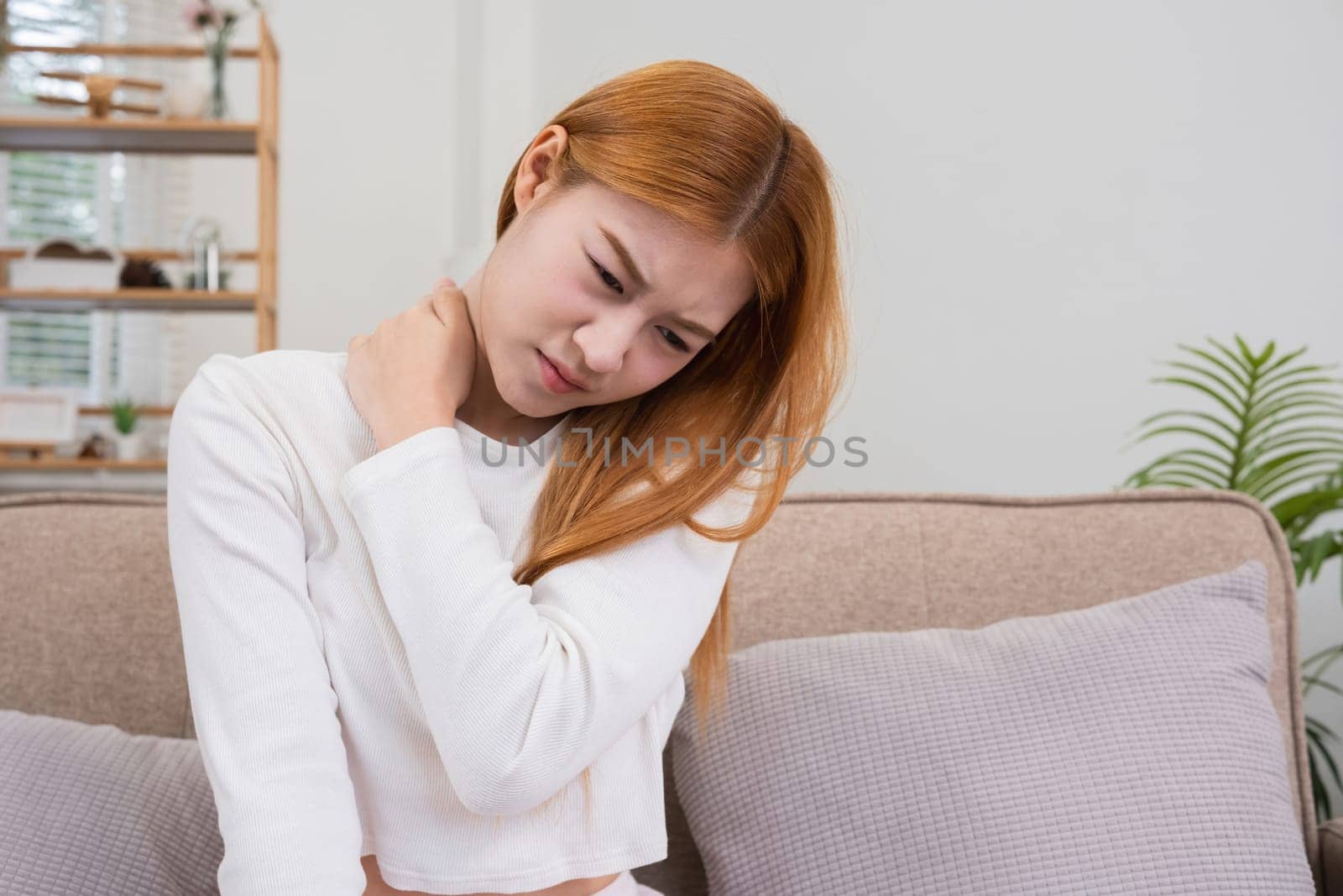 Shoulder pain. A young woman with muscle problems stands holding onto her shoulder due to pain in the shoulder area. by wichayada