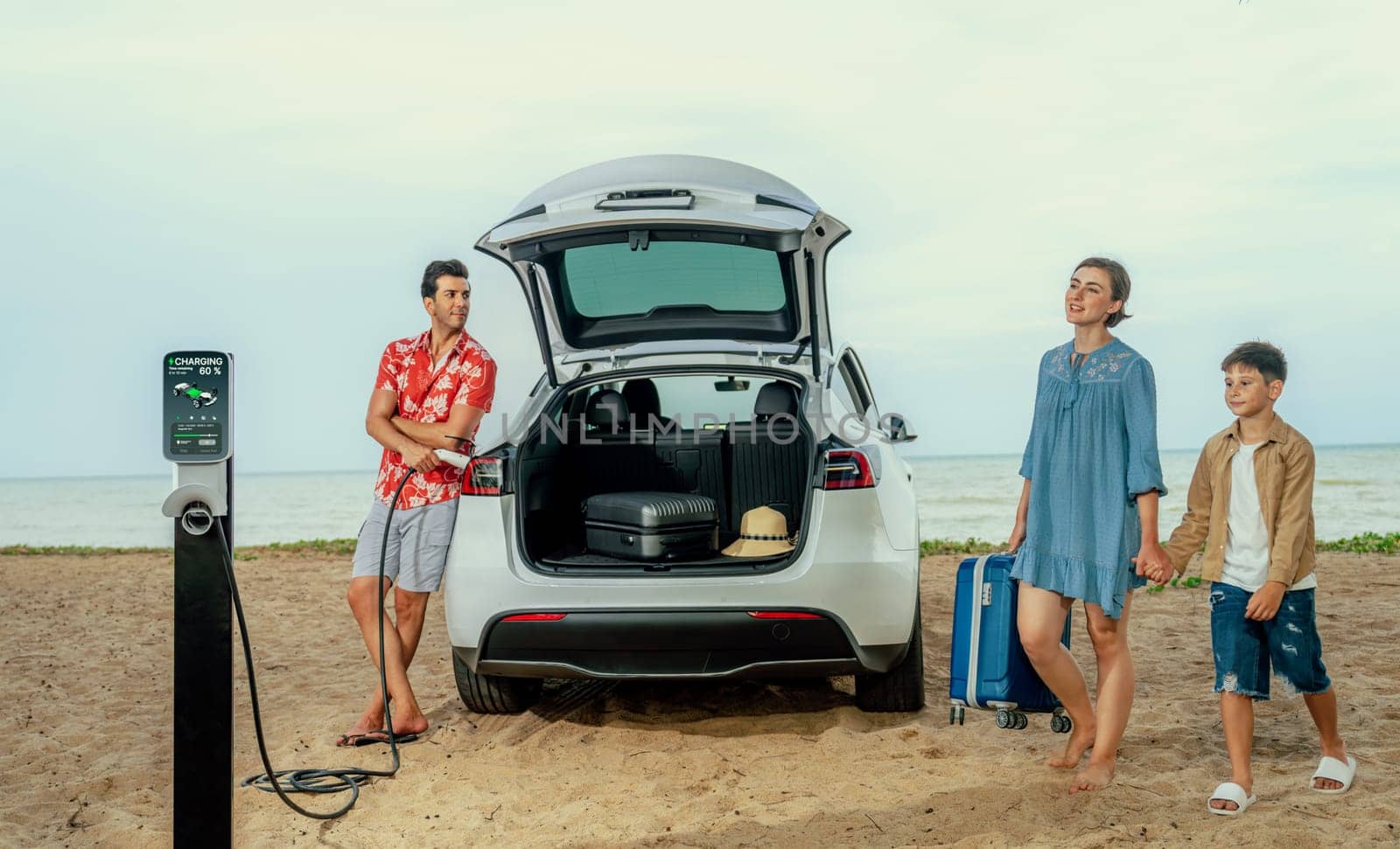 Family vacation trip traveling by the beach with electric car, lovely family taking luggage out while charging EV car battery with clean energy. Alternative family travel by eco-friendly car.Perpetual